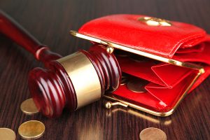 Red wallet and gavel on wooden surface, symbolizing legal financial issues.