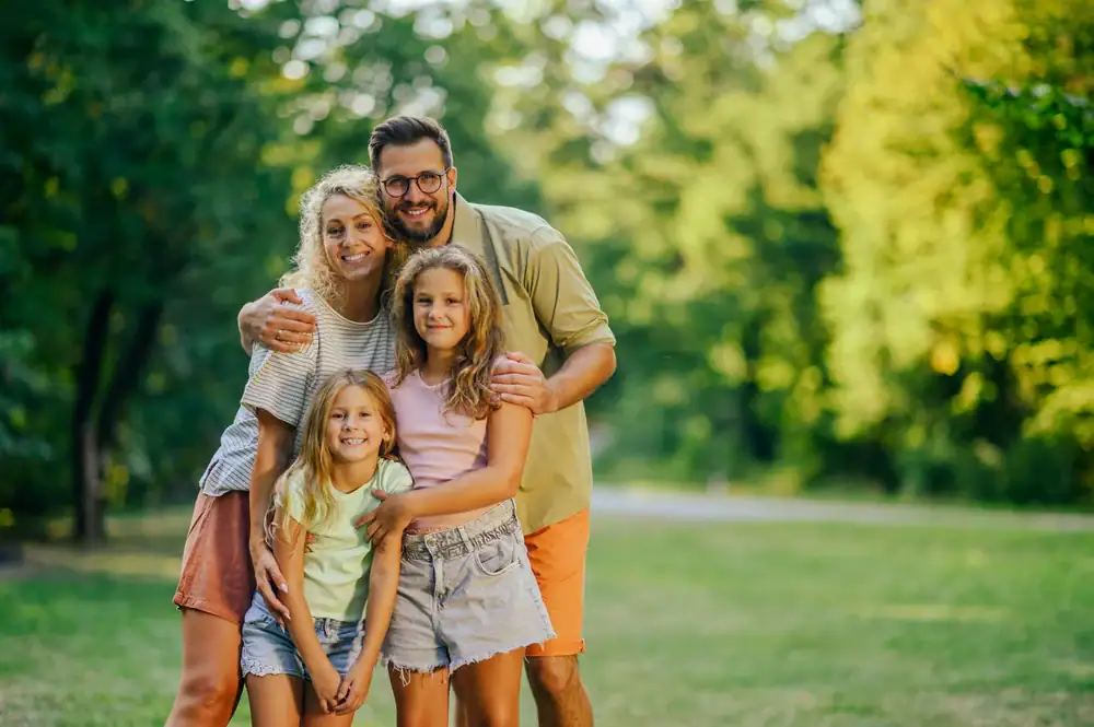 A family standing proudly together in front of their brick home