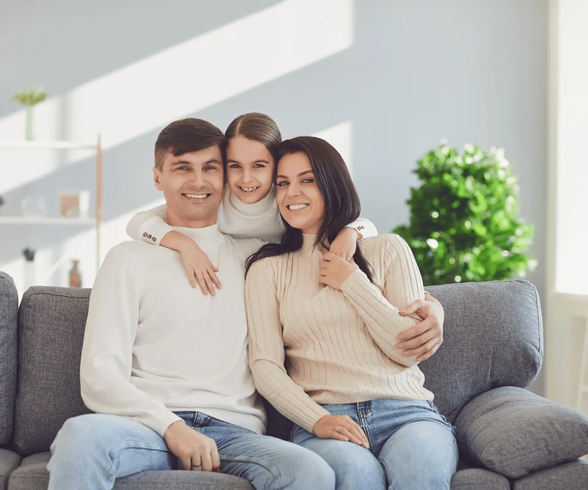 A family sharing a warm hug by a sunny window inside their home