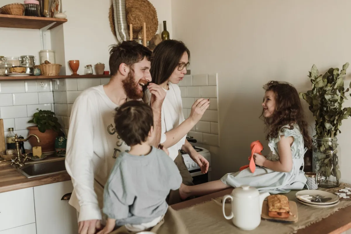 A happy family laughing together while cooking and baking in their bright home kitchen