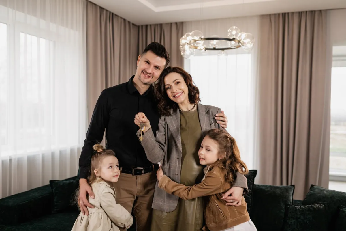 A joyful family standing together in their living room holding the keys to the home they kept