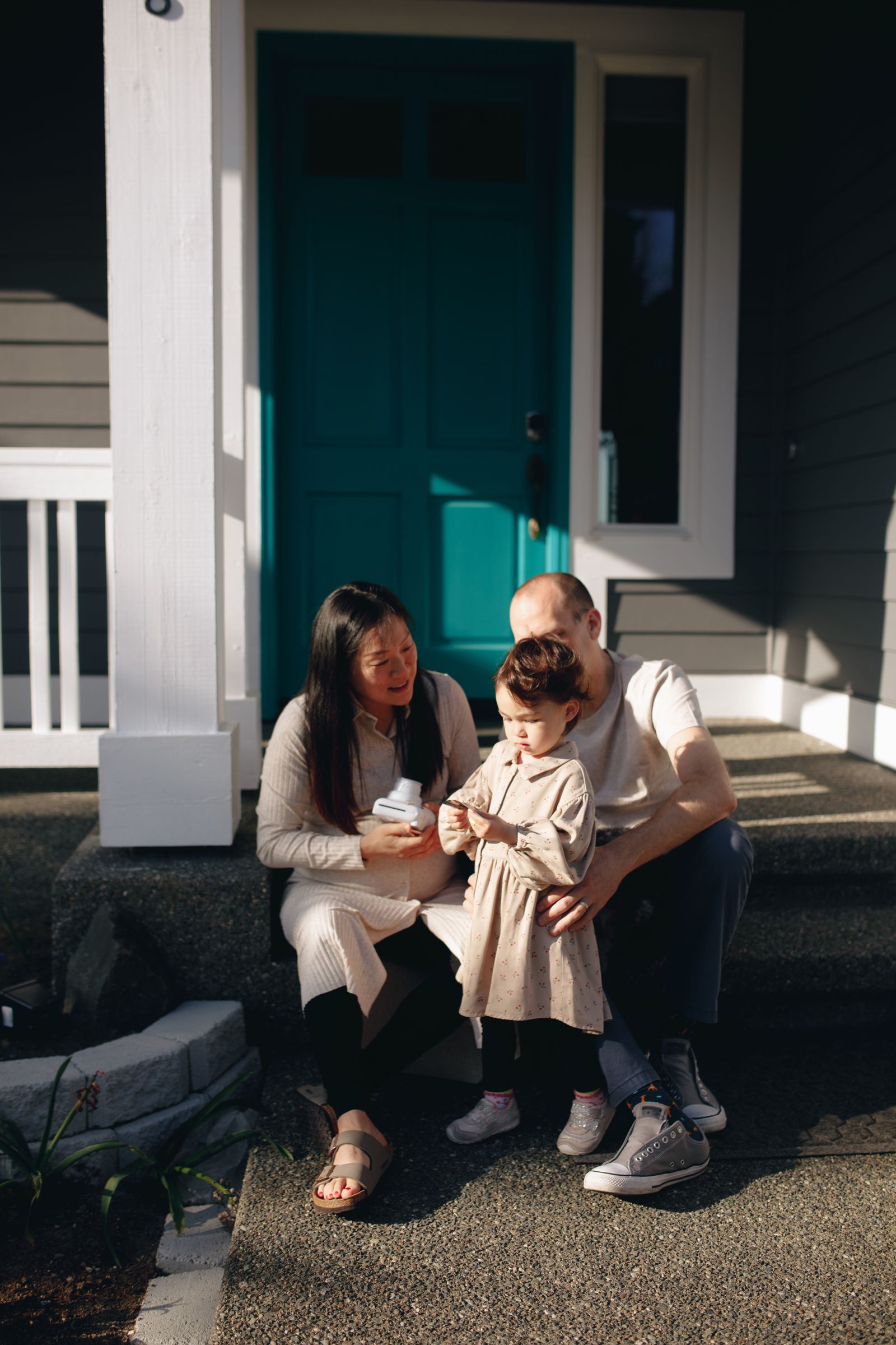A happy family relaxing together on the front porch steps of their home on a sunny day