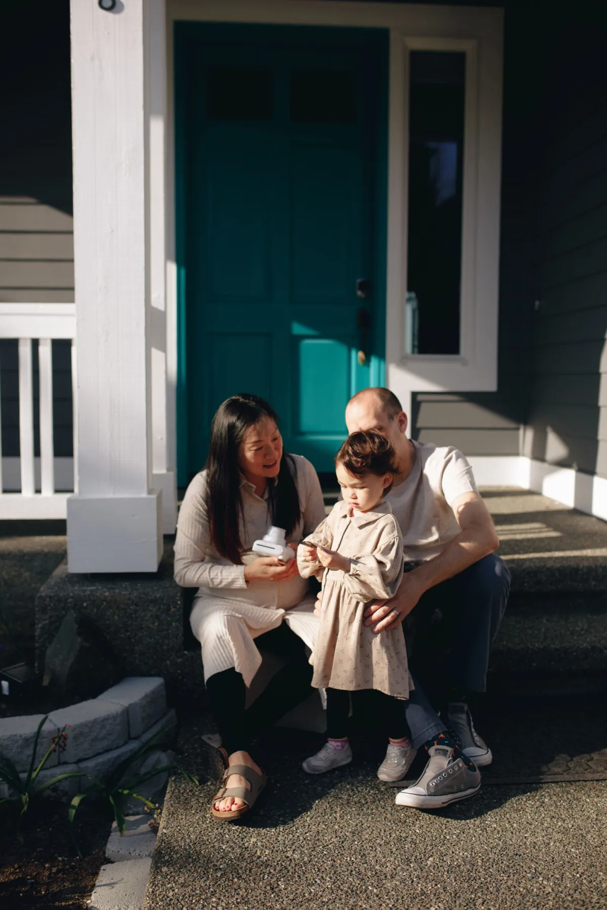 A happy family relaxing together on the front porch steps of their home on a sunny day