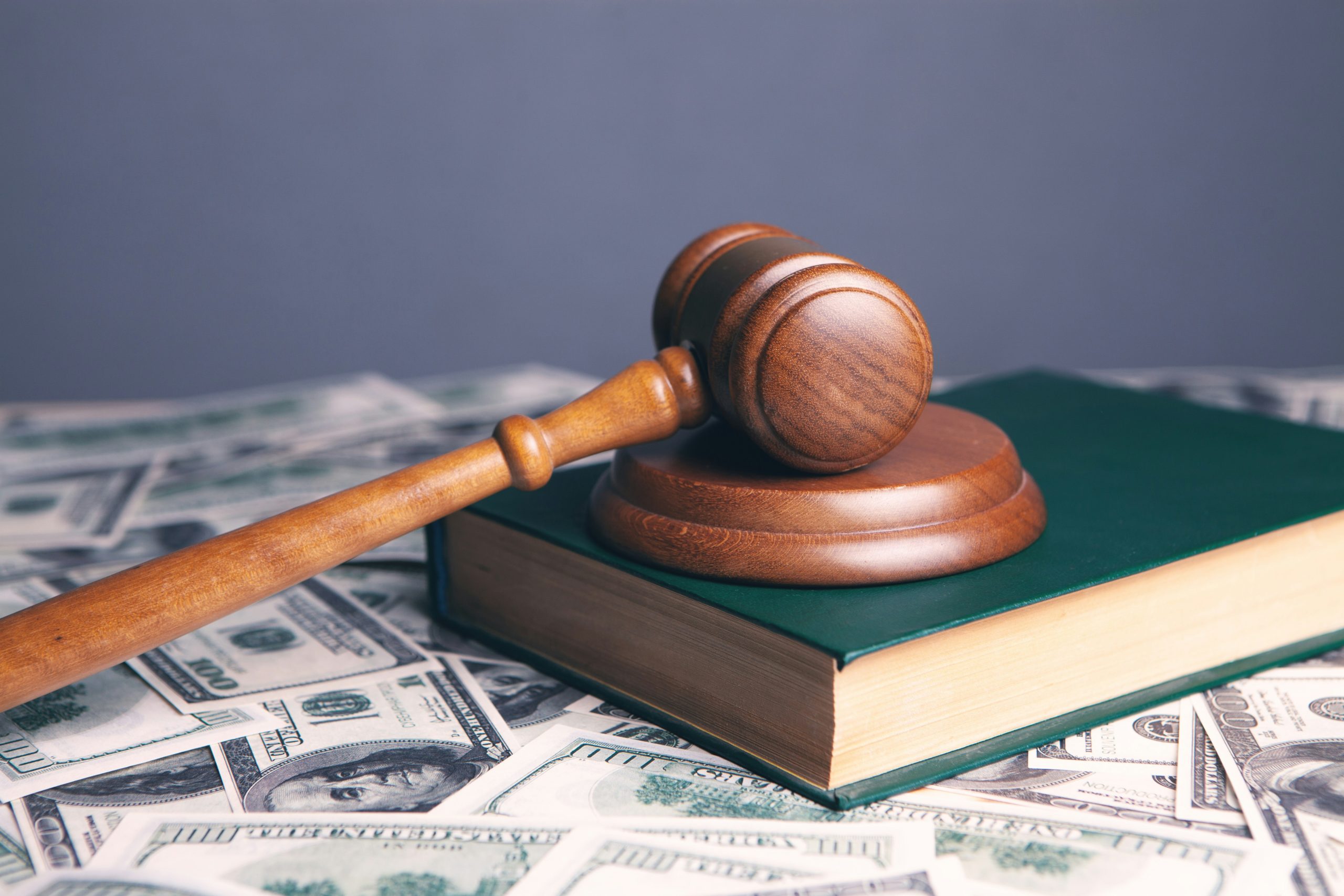 A judge’s gavel and book are placed on cash, representing Foreclosure Attorneys Long Island & NYC.