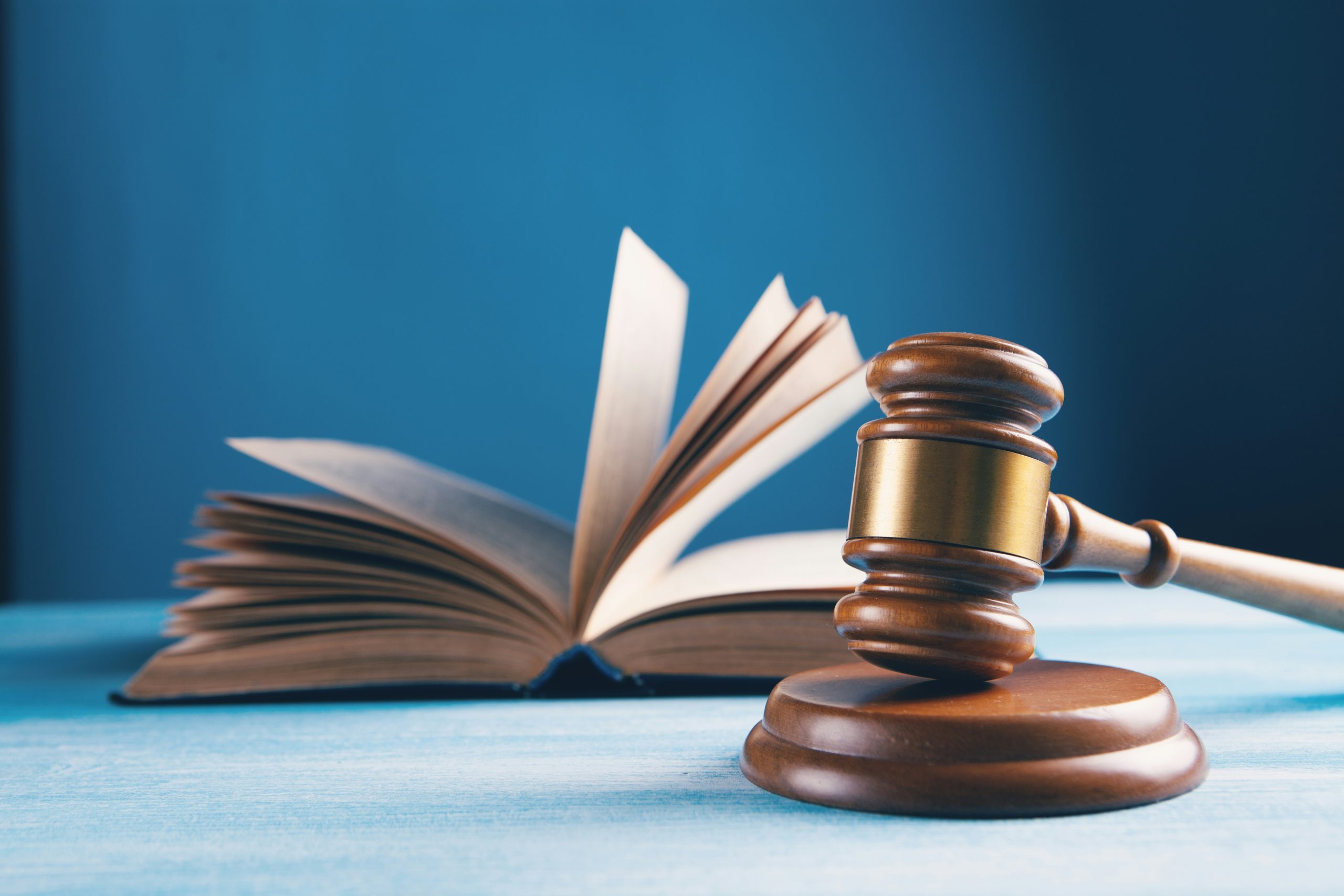 A wooden gavel and open book rest on a blue table, symbolizing Bankruptcy Attorneys in Long Island.