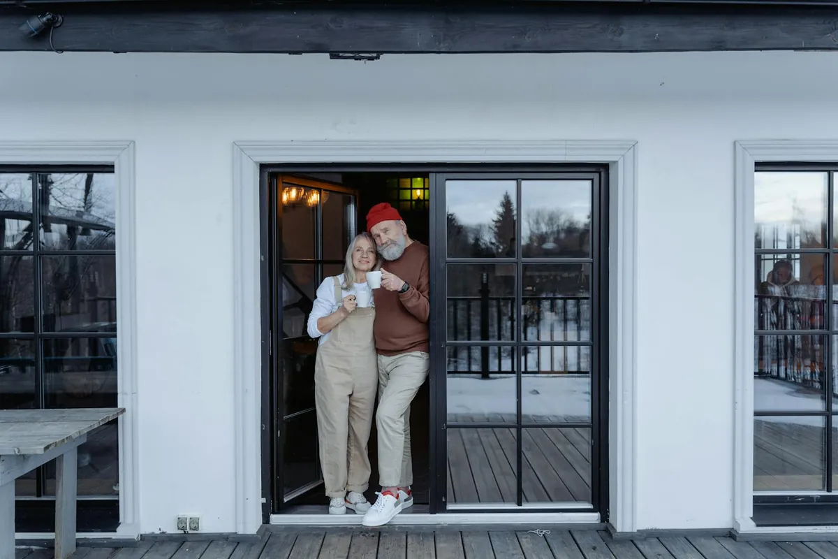 An older couple smiling on their home porch with coffee