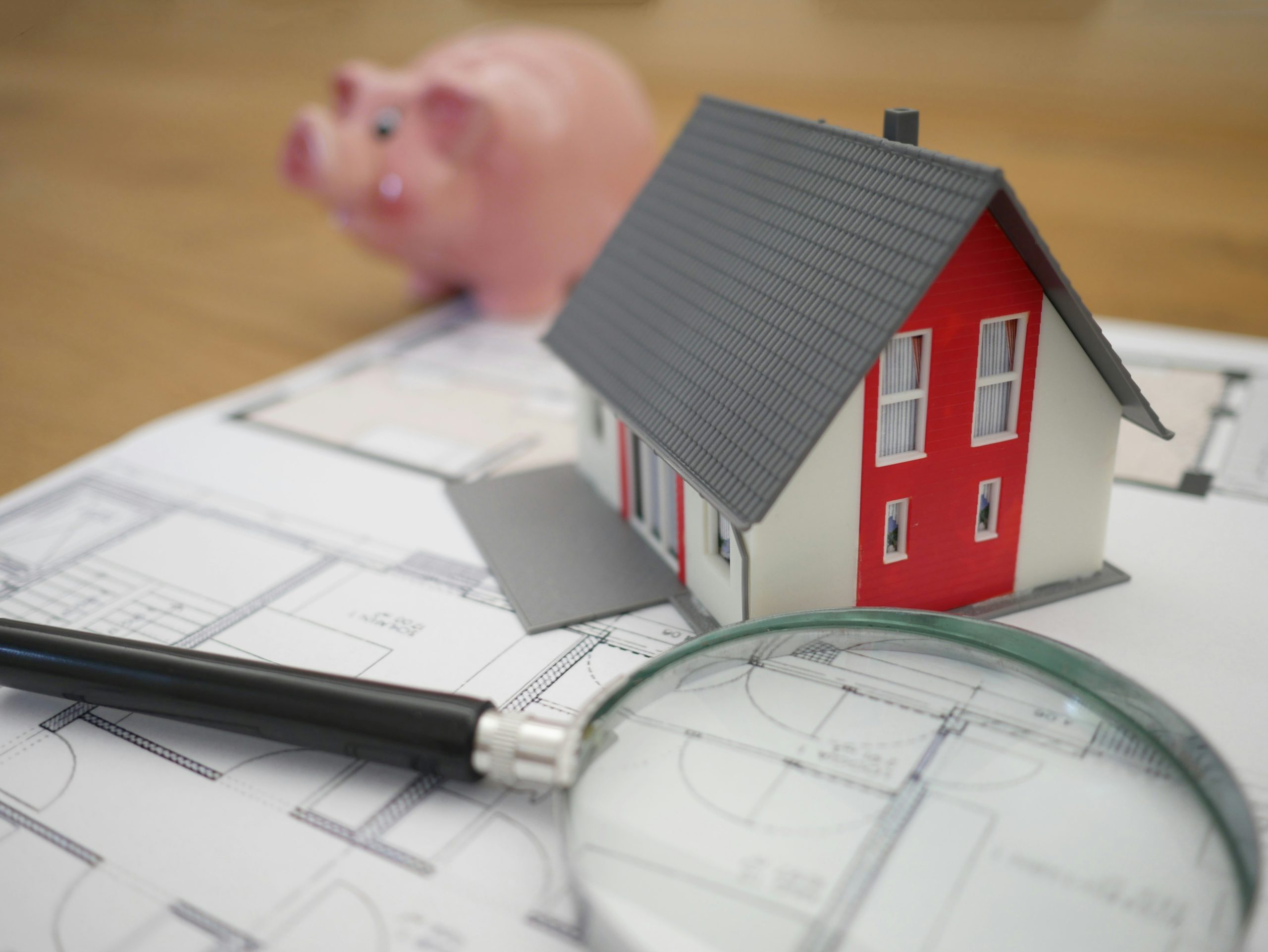A model house, pen, and magnifying glass rest on blueprints for bankruptcy attorneys in Long Island.
