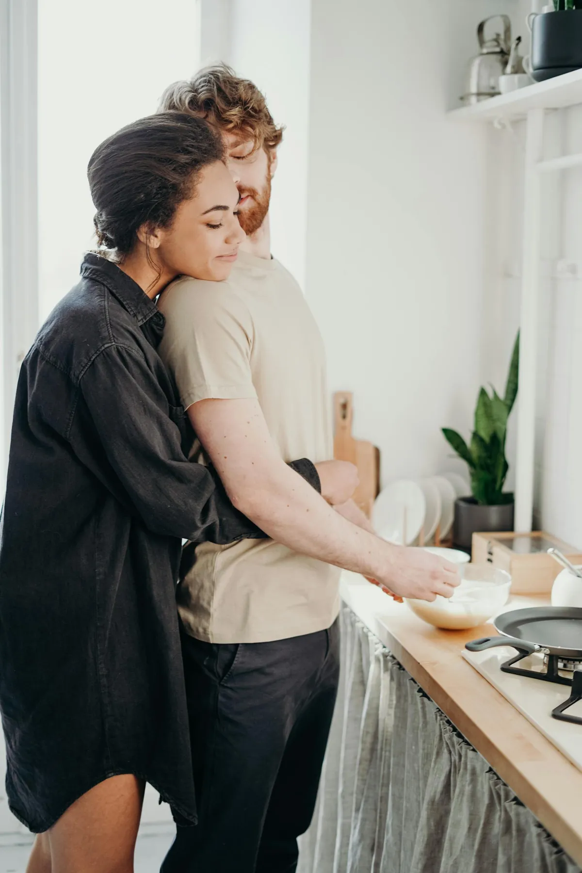 A couple embracing in their bright sunny kitchen